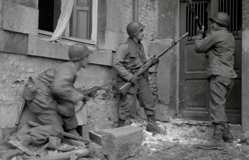 Three Americans of the 117th Infantry Regiment are about to enter a house where several enemy snipers are holding out. 